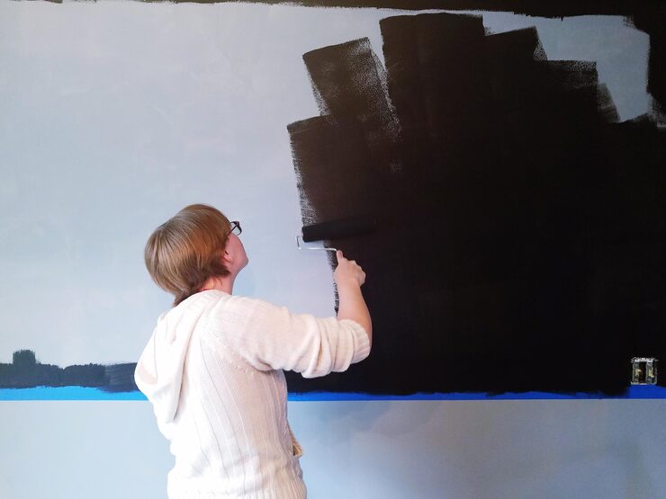 rear view young woman painting wall