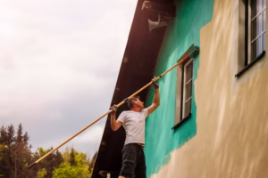 worker paints facade walls house