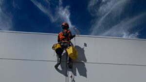 Back view of a worker painting a building wall outdoors in Auckland, New Zealand.