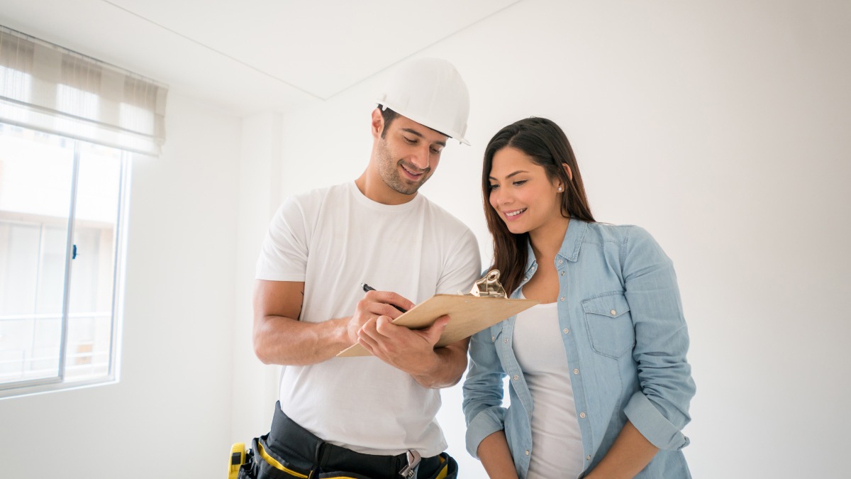 Contractor in a hard hat reviewing a clipboard checklist with a client