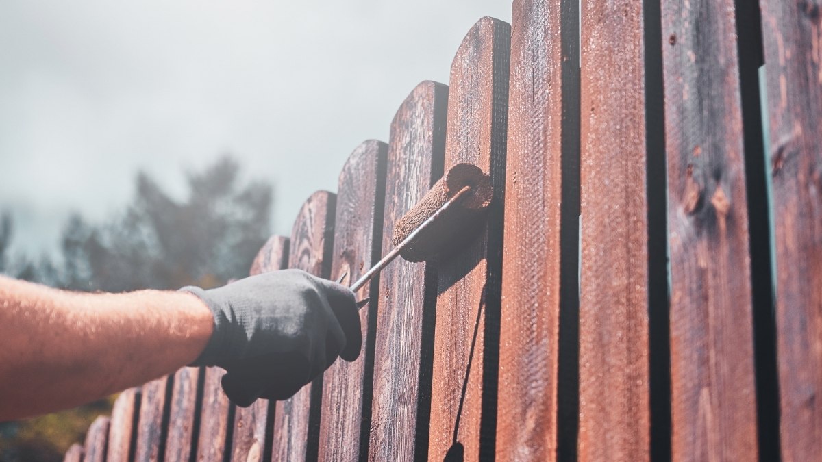 using a small paint roller to apply a dark brown finish
