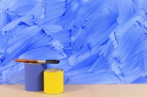 A Blue Painted Wall with a Paint Brush and Paint in Front