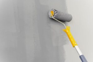 Painting A Wall with Gray Paint and a Roller
