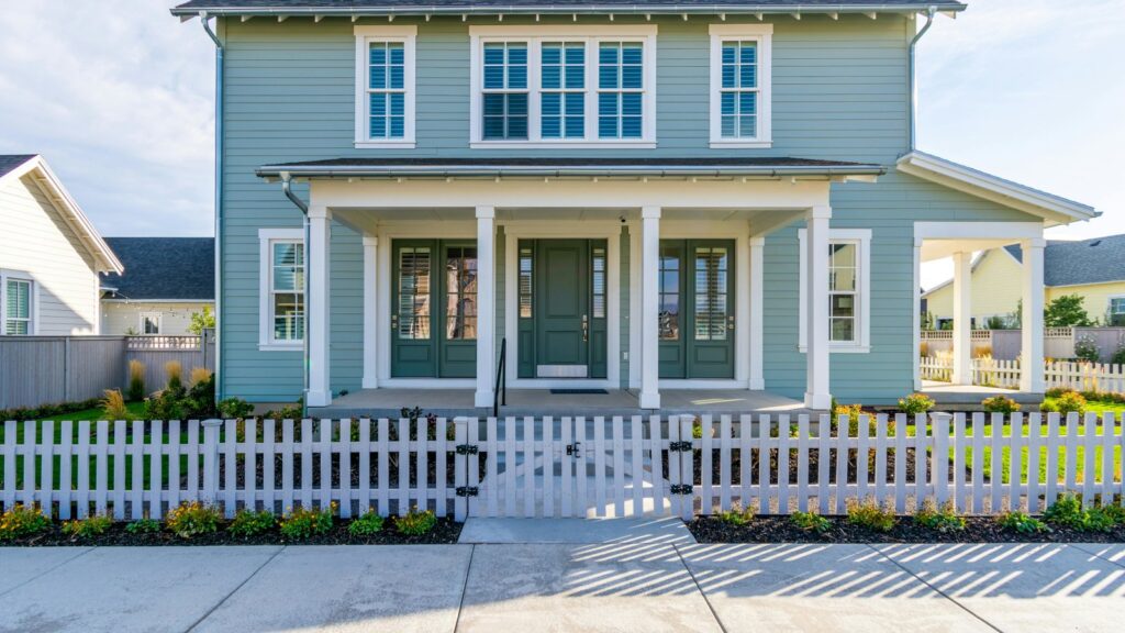 Modern suburban house with a white picket fence in a quiet neighborhood, showcasing fresh exterior paint.