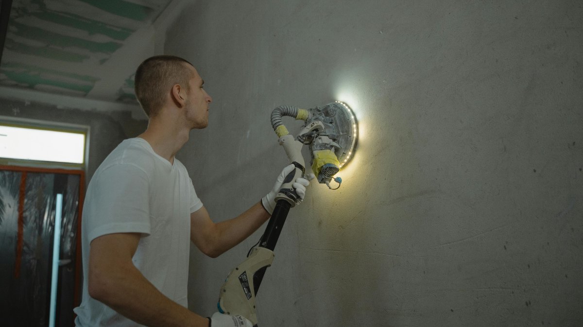 Man sanding a wall to prepare surface for interior painting