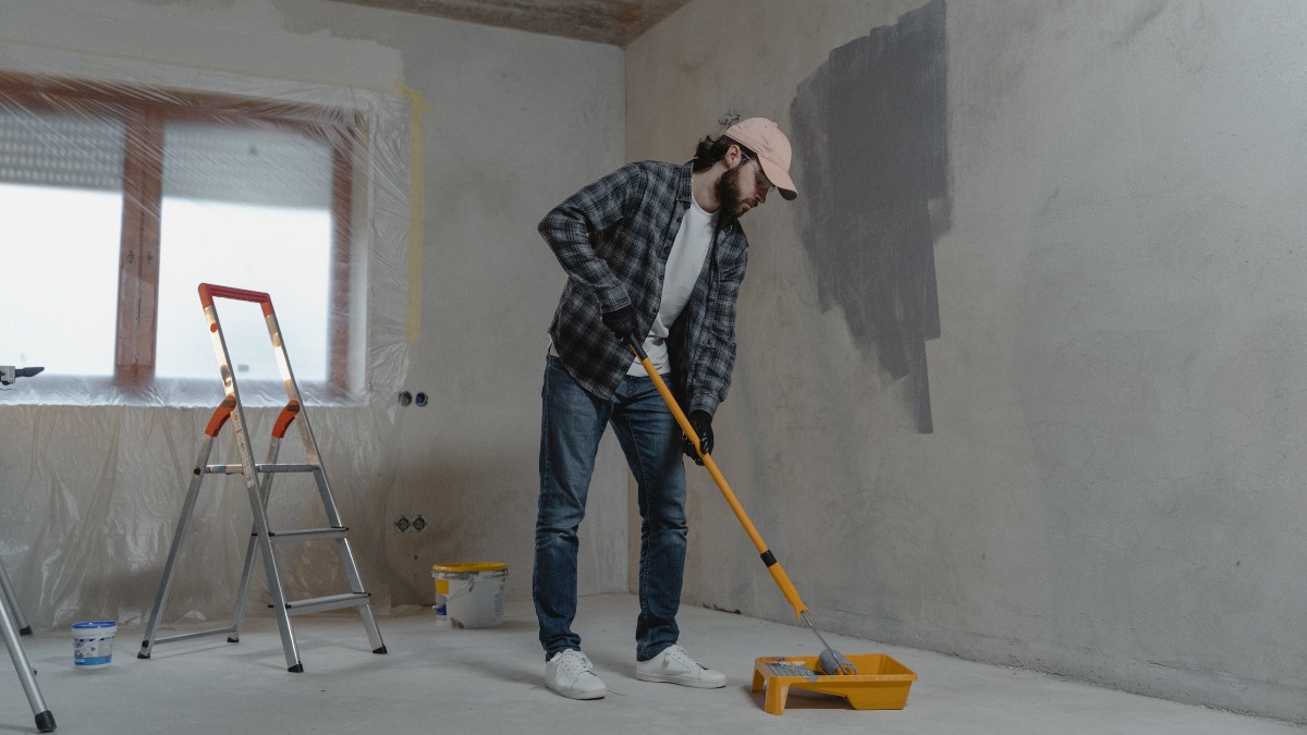 Painter loading a roller with grey paint