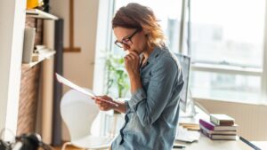 Woman with glasses in a denim shirt reviewing a document
