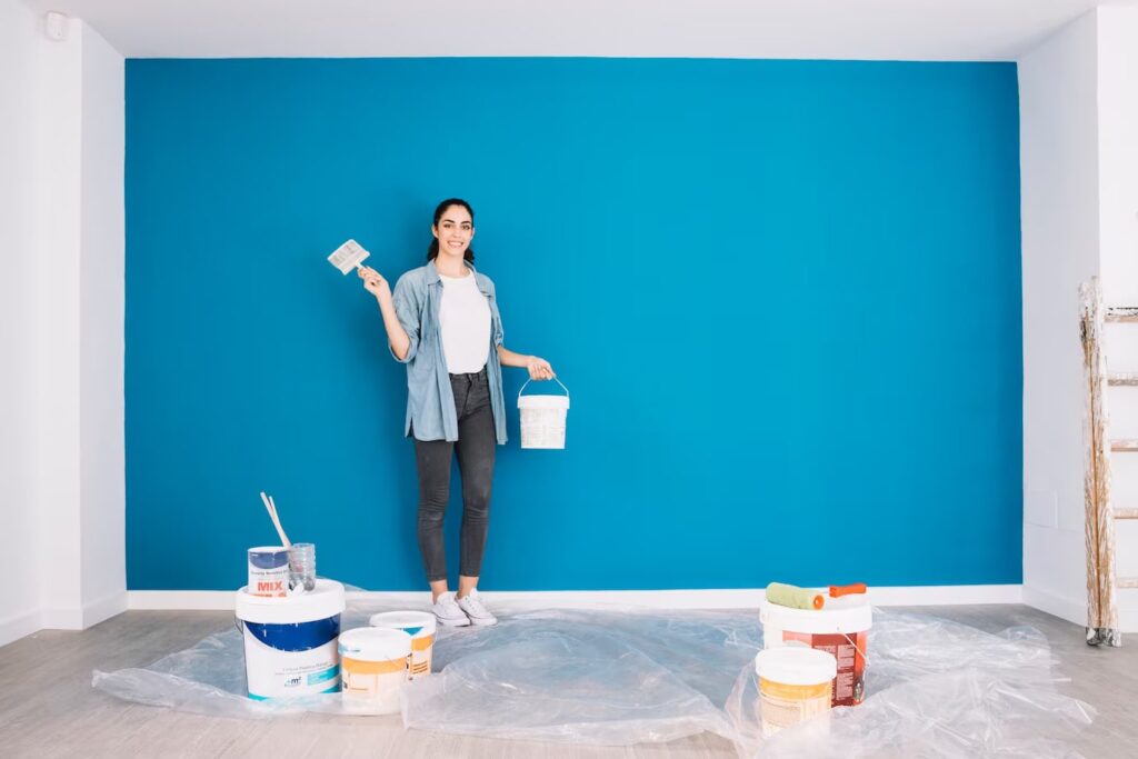 Woman Painting a wall with paints on the floor