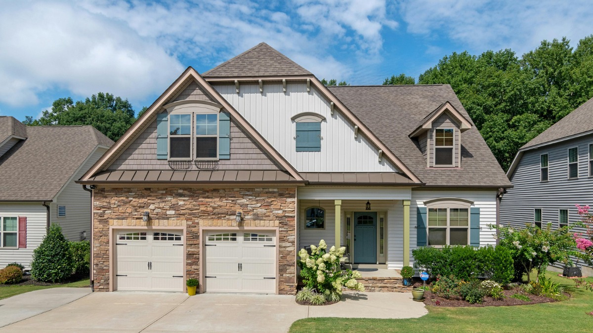 two-story house featuring stone accents and light cream exterior paint