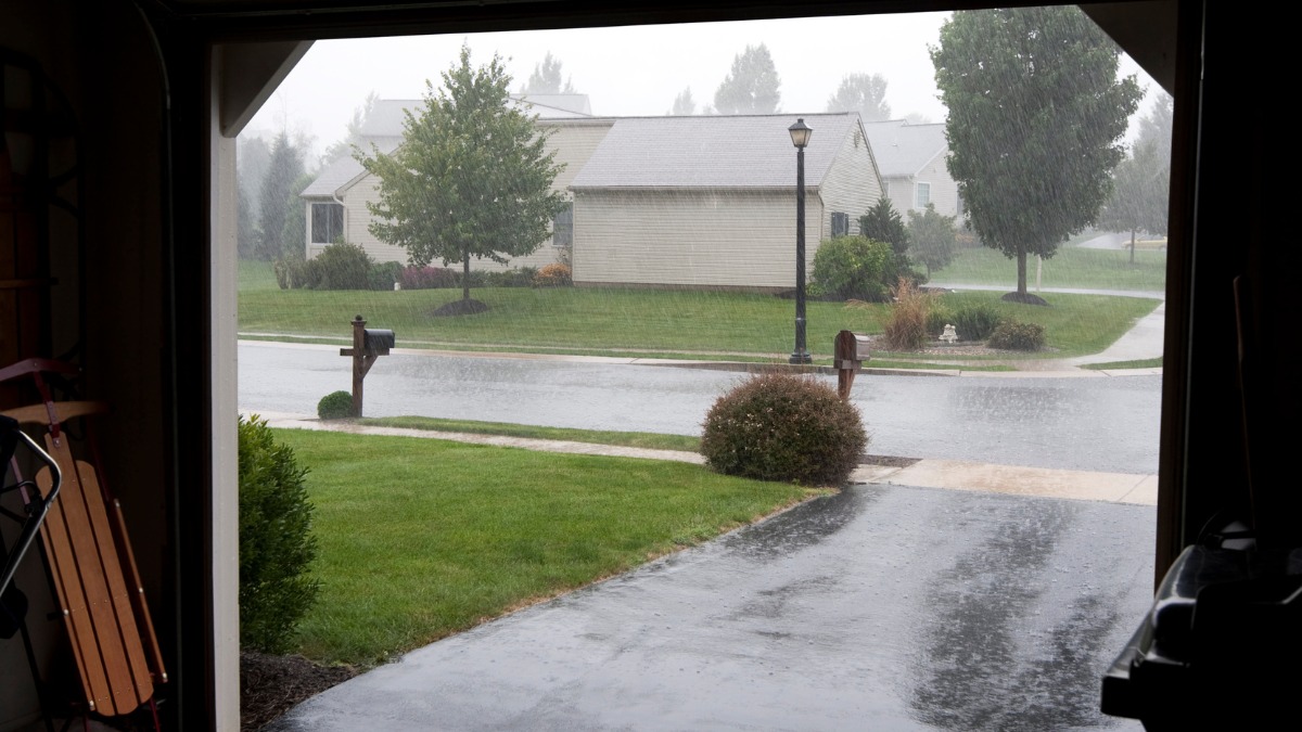 View from a dark garage looking out at a heavy rainstorm
