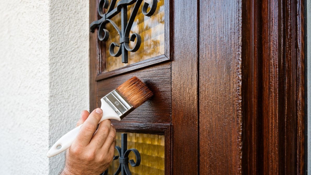 using a paintbrush to apply a dark wood stain